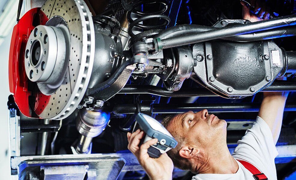 Mechanic looking under a hoisted Land rover